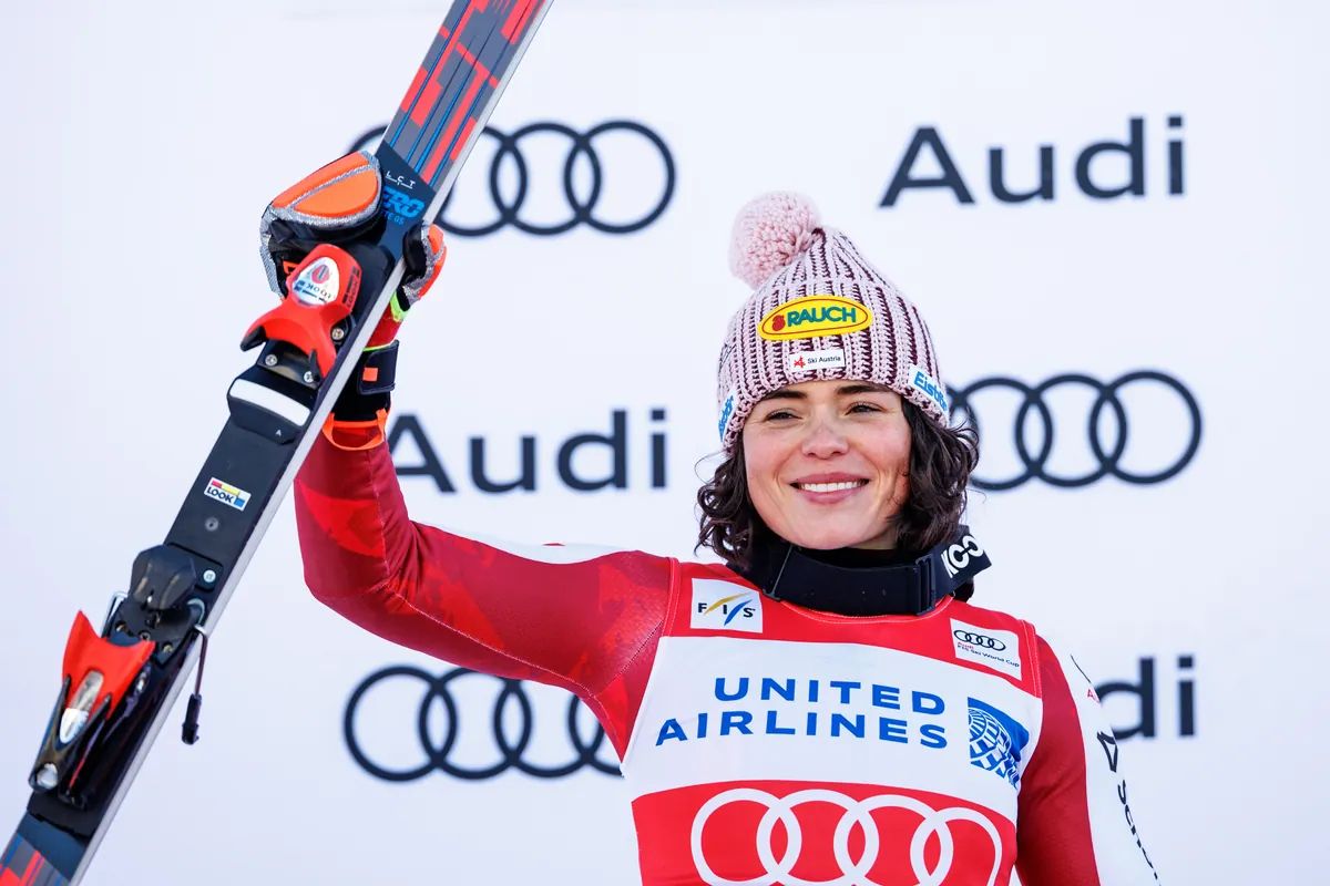 Julia Scheib auf dem Podium mit erhobenem Ski
