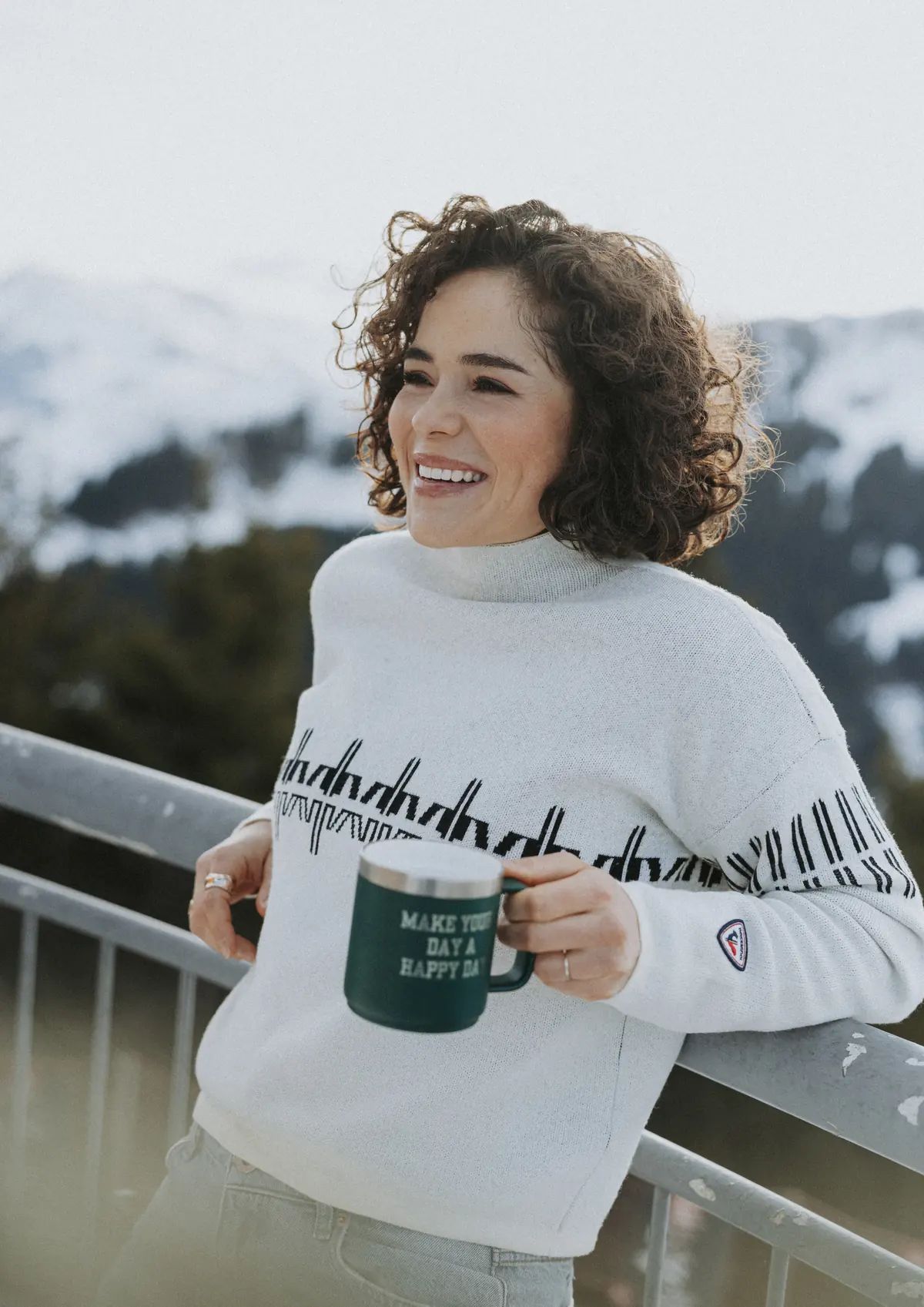 Julia Scheib lachend mit Tasse vor Bergpanorama
